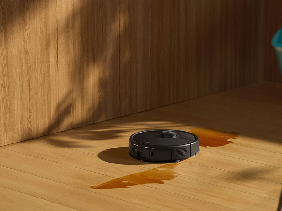 Saugroboter Roborock Q7 TF Schwarz reinigt verschüttete Flüssigkeit auf einem Holzboden in modernem Interieur