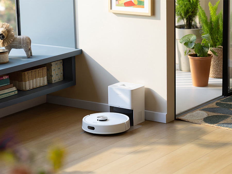 Saugroboter Roborock Q7 TF Weiß kehrt zur Dockingstation an einer Wand in einem hellen, gemütlichen Raum zurück