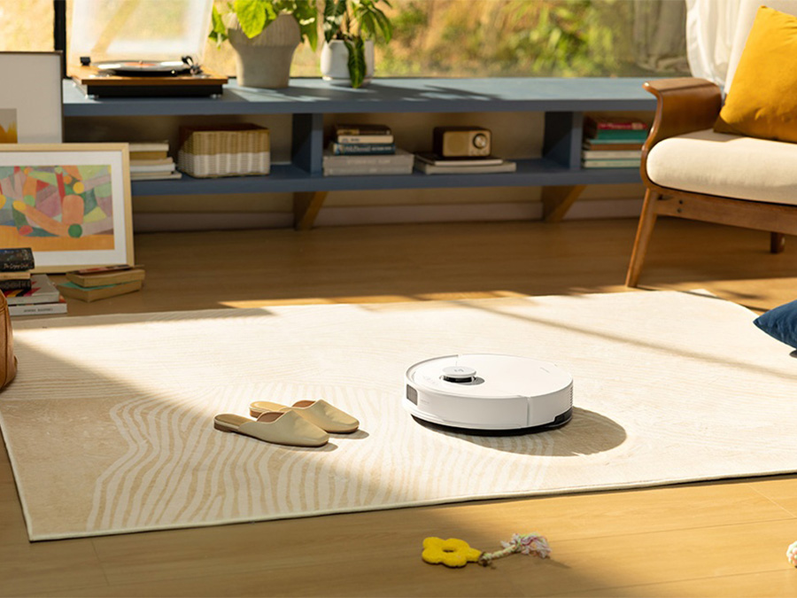 Der Staubsaugerroboter Roborock Q10 PF White saugt einen hellen Teppich in einem modernen Interieur mit hellem Parkett