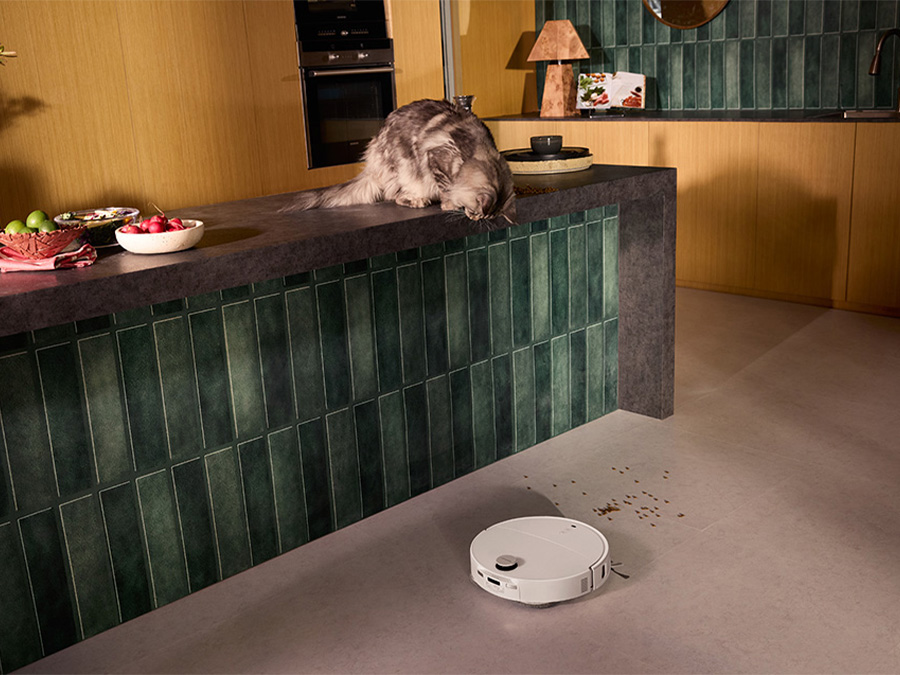 Frau und Mann im Wohnzimmer mit Katze, während der Saugroboter Roborock Qrevo Edge T Weiß leise einen Holzboden reinigt