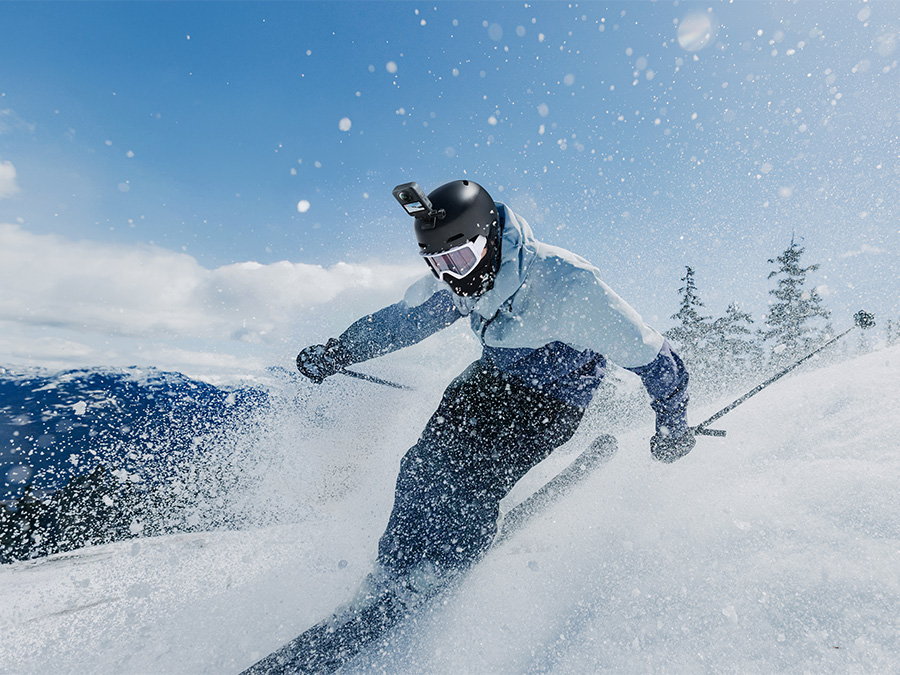 Skifahrer mit DJI Osmo 360 Standard Combo auf dem Helm bei einer dynamischen Abfahrt an einem sonnigen Tag
