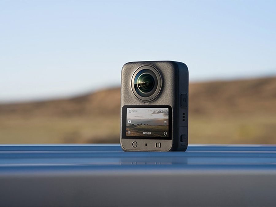 DJI Osmo 360 Kamera auf Metallfläche vor Landschaft mit Objektivschutz