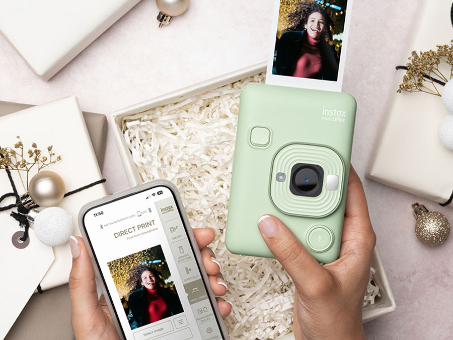Grüne Fujifilm Instax Mini LiPlay Kamera neben Smartphone mit Druck-App