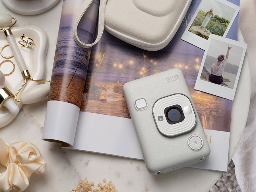 Weißer Fujifilm Instax mini LiPlay auf dem Tisch mit Accessoires und gedruckten Fotos