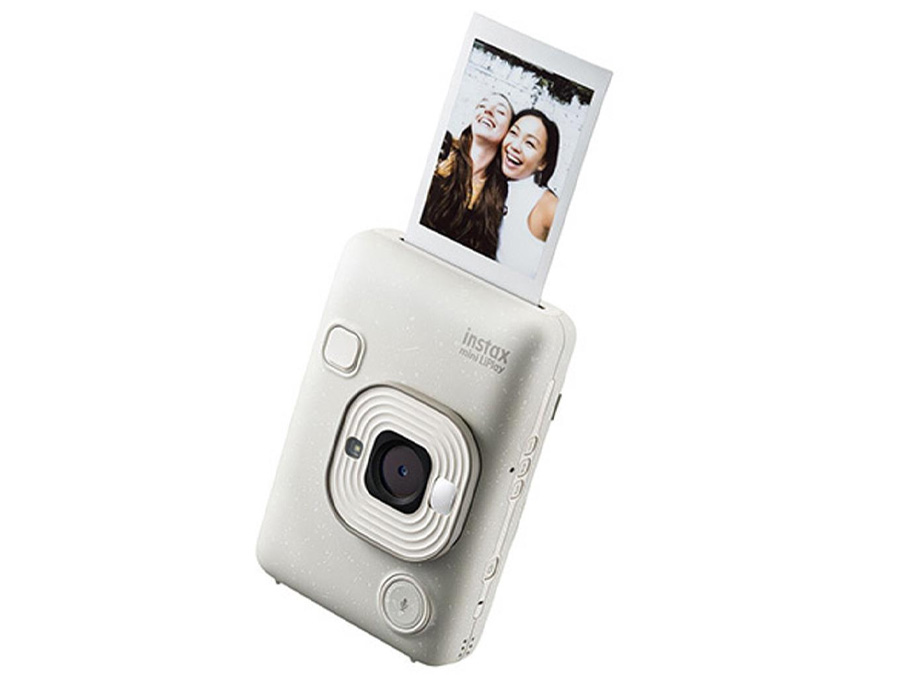 Weißer Fujifilm Instax mini LiPlay auf dem Tisch mit Accessoires und gedruckten Fotos
