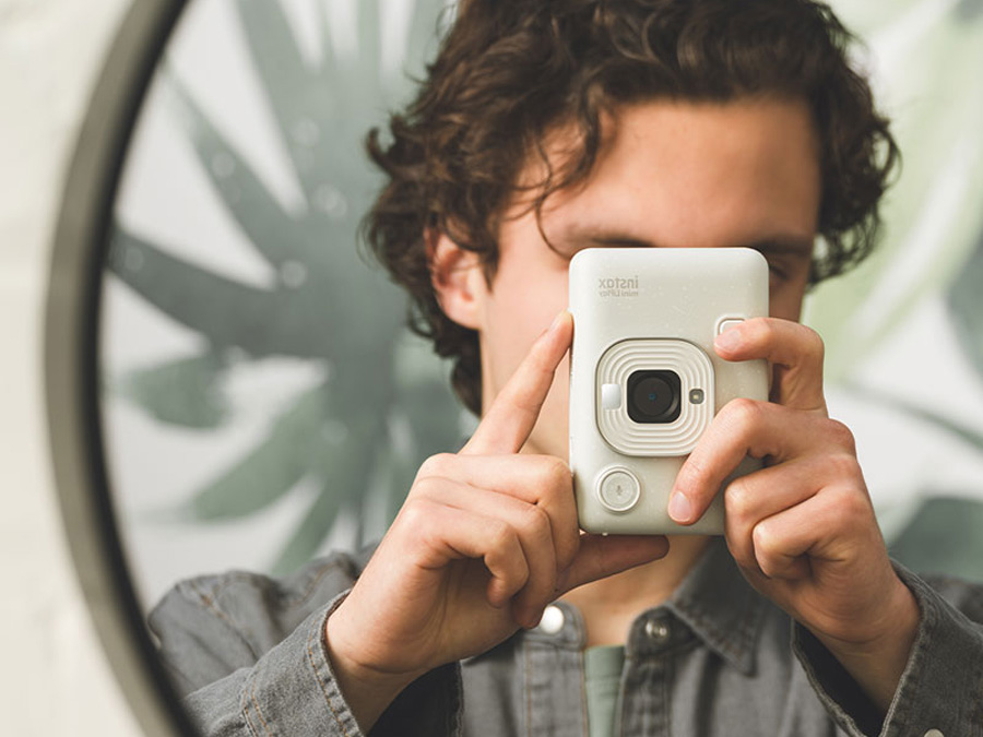 Mann hält weißen Fujifilm Instax mini LiPlay in den Händen