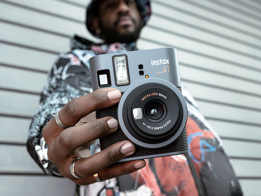 Nahaufnahme der Hände, die die Fujifilm Instax mini 41 mit sichtbarem Einstellring halten