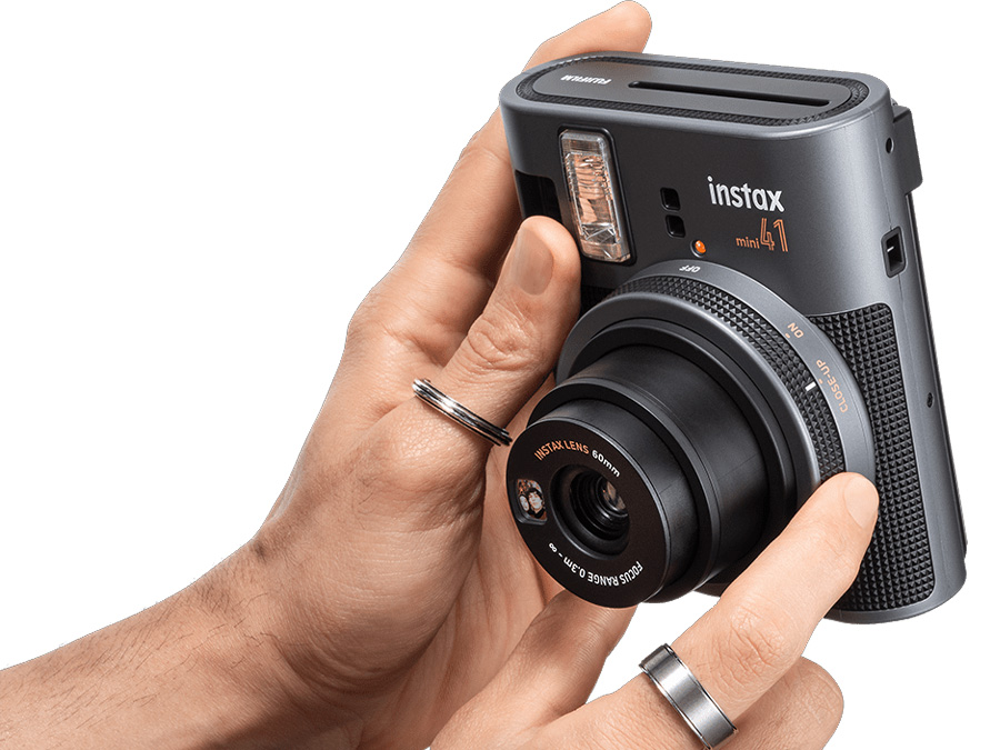 Männlicher Nutzer zeigt die in der Hand gehaltene Fujifilm Instax mini 41 mit sichtbarem Fokusring