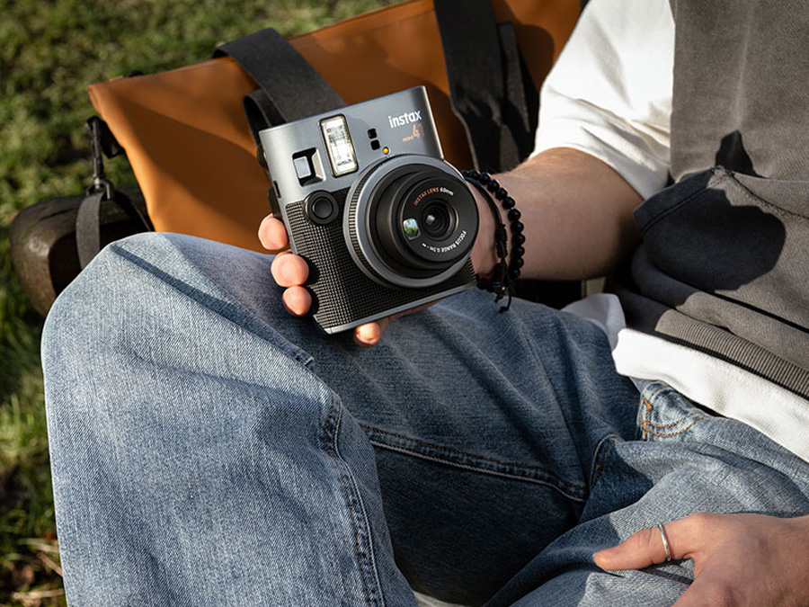 Nutzer sitzt auf einer Bank und hält die Fujifilm Instax mini 41 in der Hand