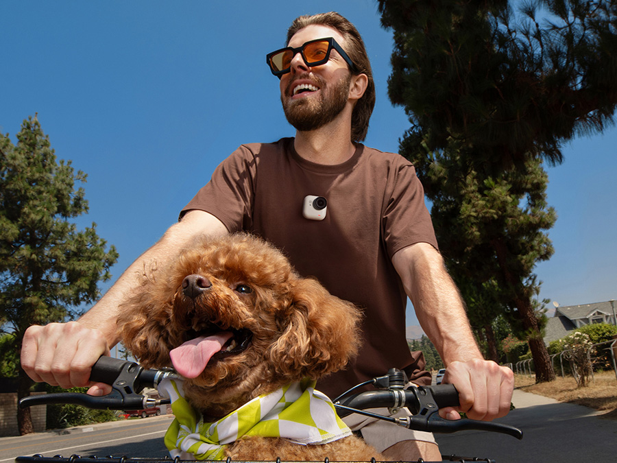 Mann fährt Fahrrad mit einem Hund auf dem Lenker, an dessen Kleidung die Insta360 GO Ultra befestigt ist