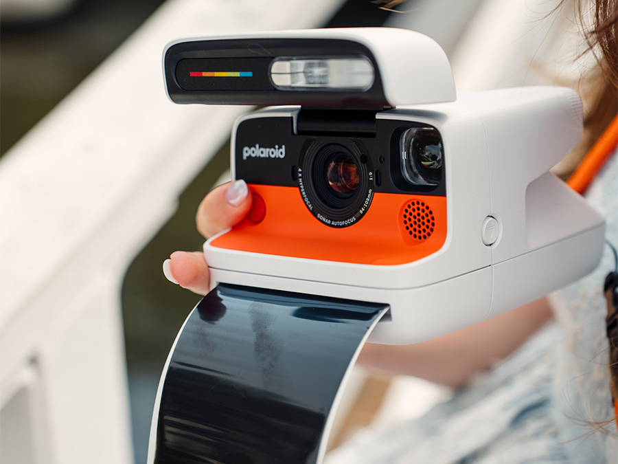 Sofortbildkamera Polaroid Flip in Weiß mit orangefarbenem Front, die frisch gedrucktes Foto zeigt