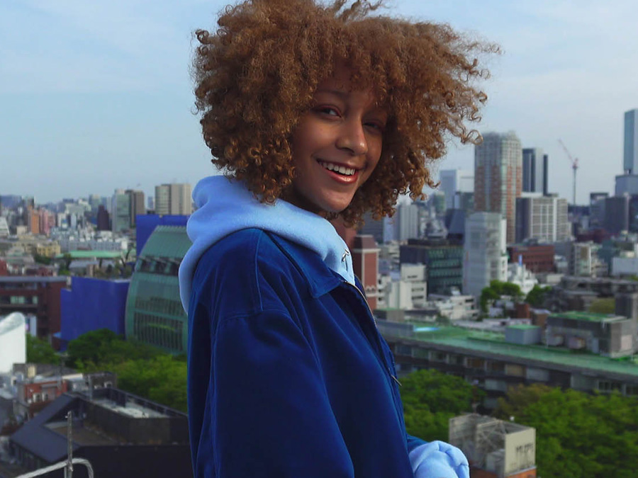 Frau posiert auf einem Dach mit Stadtpanorama im Hintergrund, aufgenommen mit der Sony ZV-1 II Kamera
