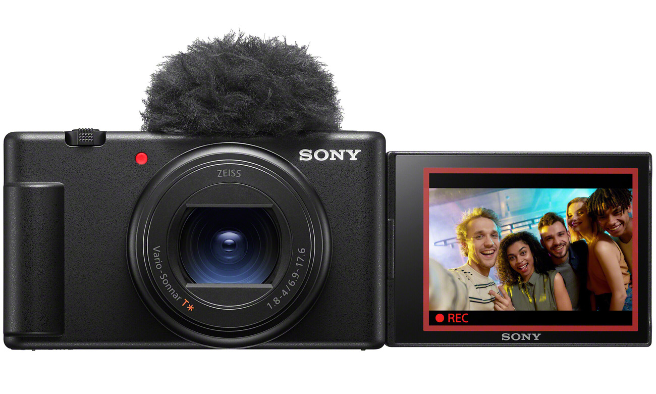 Sony ZV-1 II Kamera mit angeschlossenem Mikrofon und klappbarem Bildschirm, der eine Gruppe beim Filmen zeigt